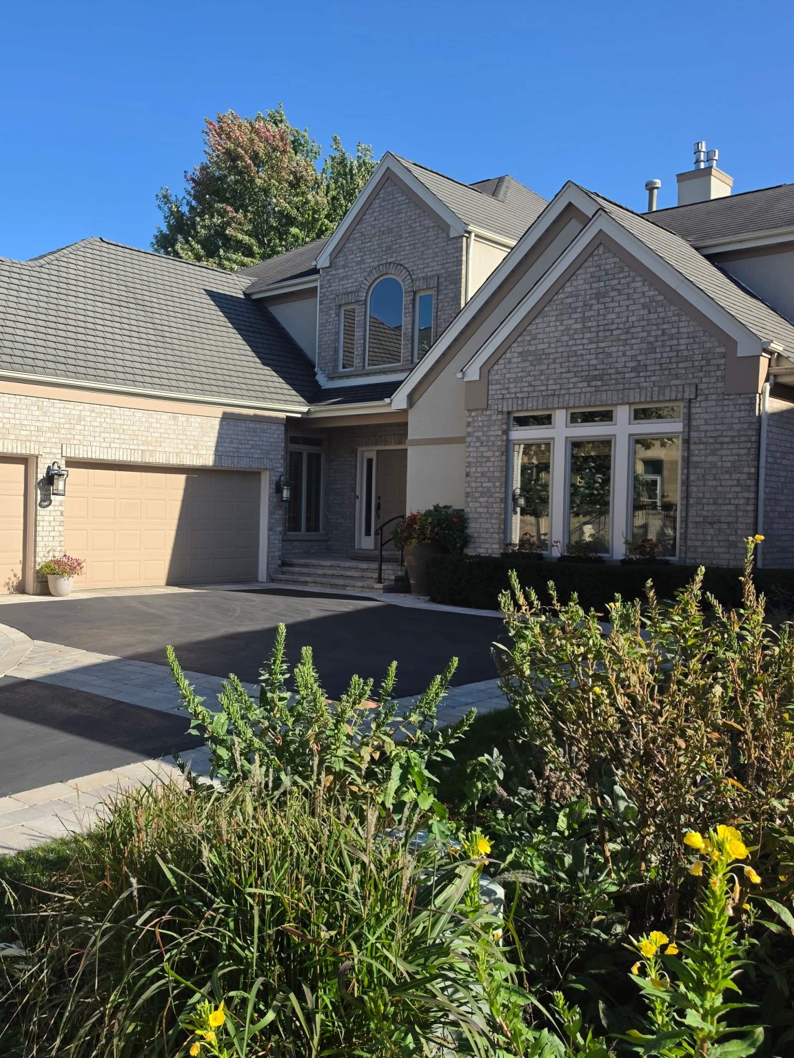 Light-brick home with gabled roofs, an attached garage and landscaped front beds in Fort Sheridan.