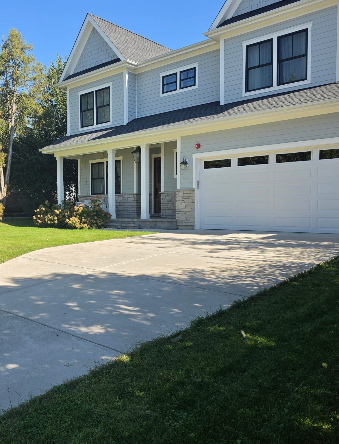 Two-story home with a front porch, attached garage and landscaped lawn in Northbrook.
