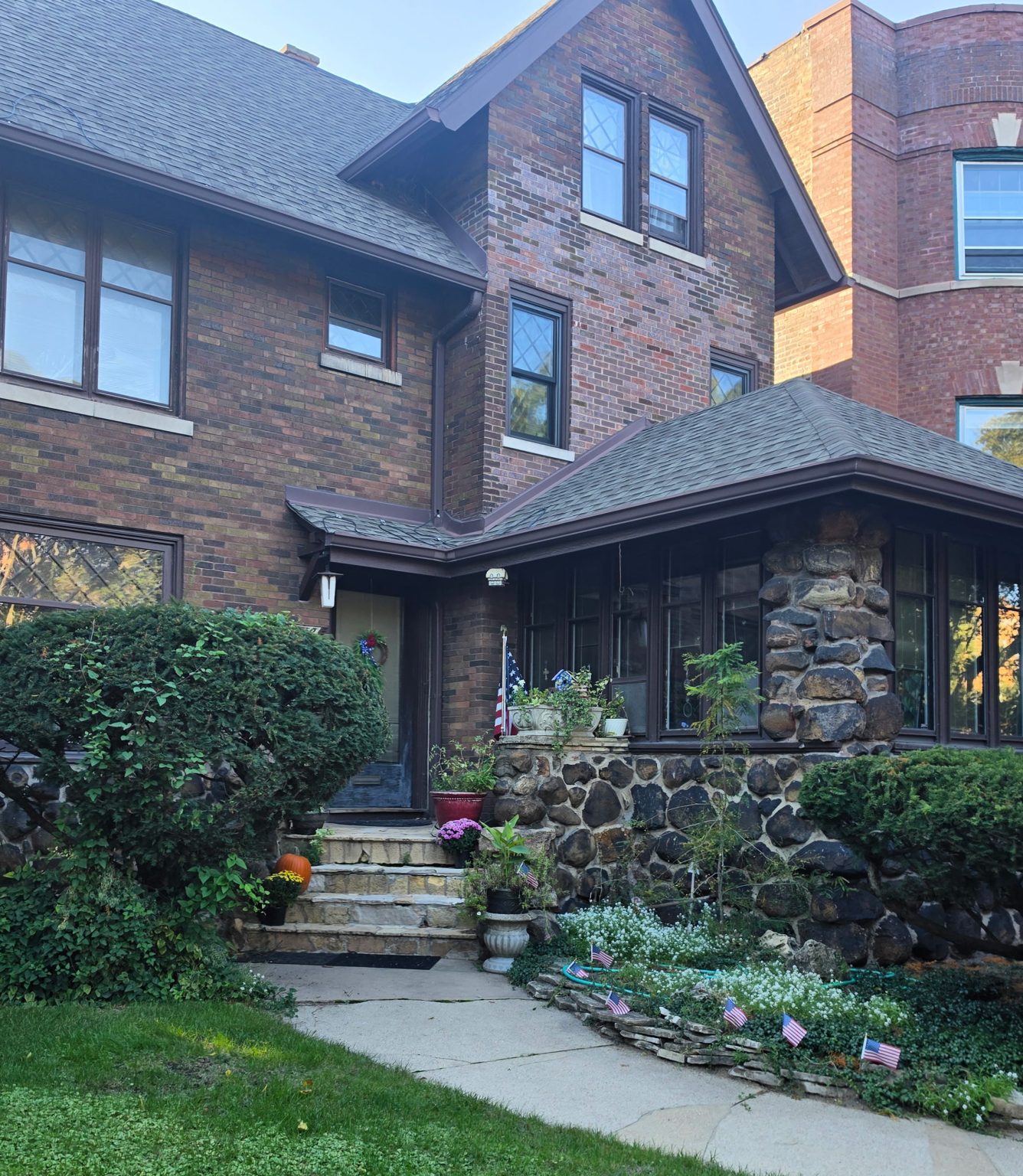 Brick home with a stone porch, front garden and neighboring apartment building in Uptown.