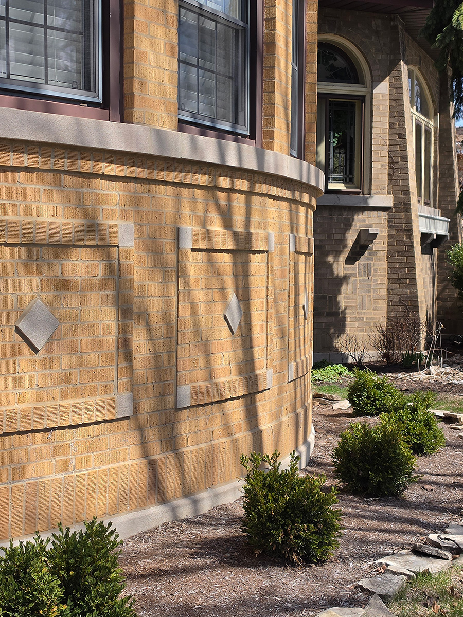 Brick residential architecture in West Ridge, Chicago, with bay windows, masonry detailing, and a landscaped side yard.
