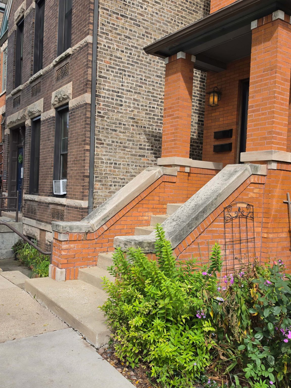 Brick residential building with a raised front porch and stone railings in Bucktown, Chicago.