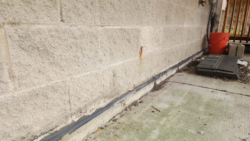 Masonry wall meeting an outdoor paved surface.