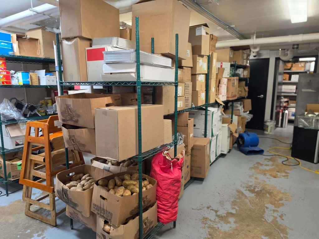 Basement storage aisle lined with green wire shelving holding boxes and supplies