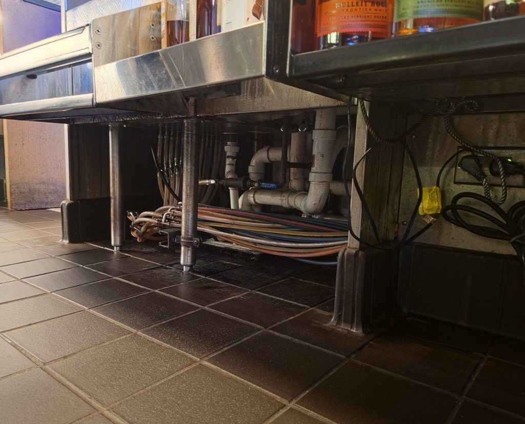 Under-bar equipment and utility area in a commercial restaurant.