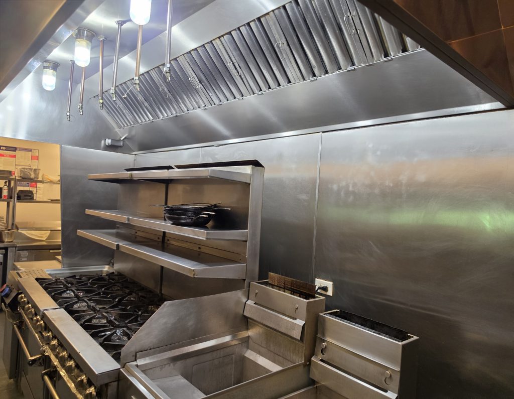 Commercial restaurant kitchen with stainless equipment and a full cook line.
