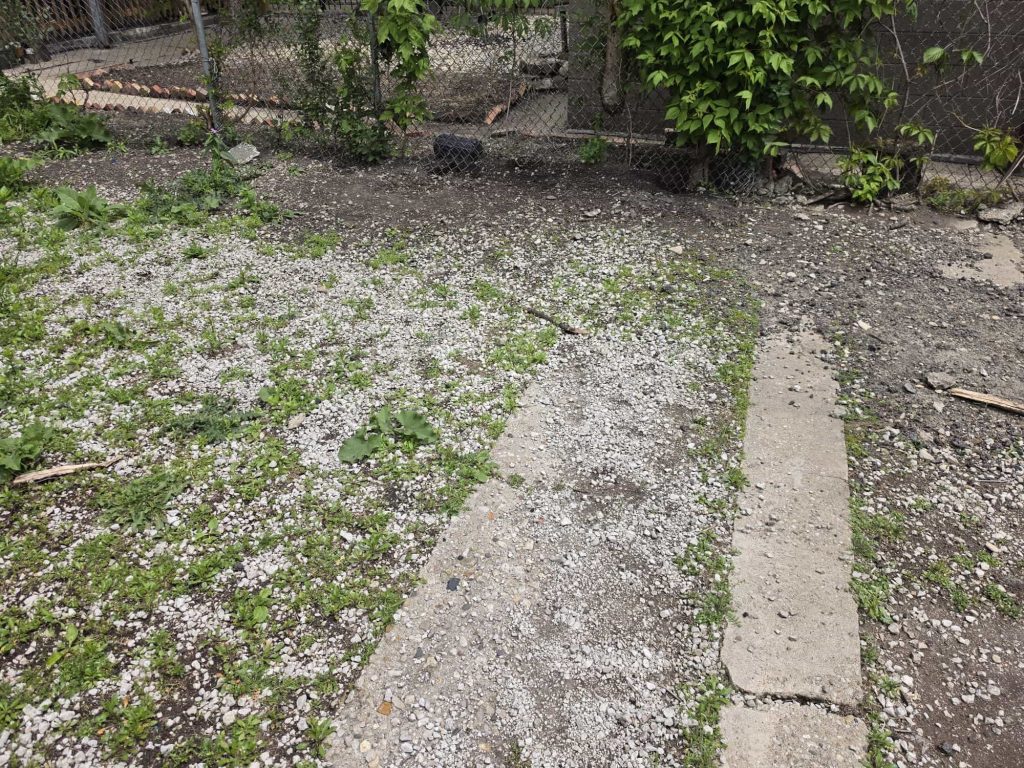 Gravel and soil along a backyard fence.