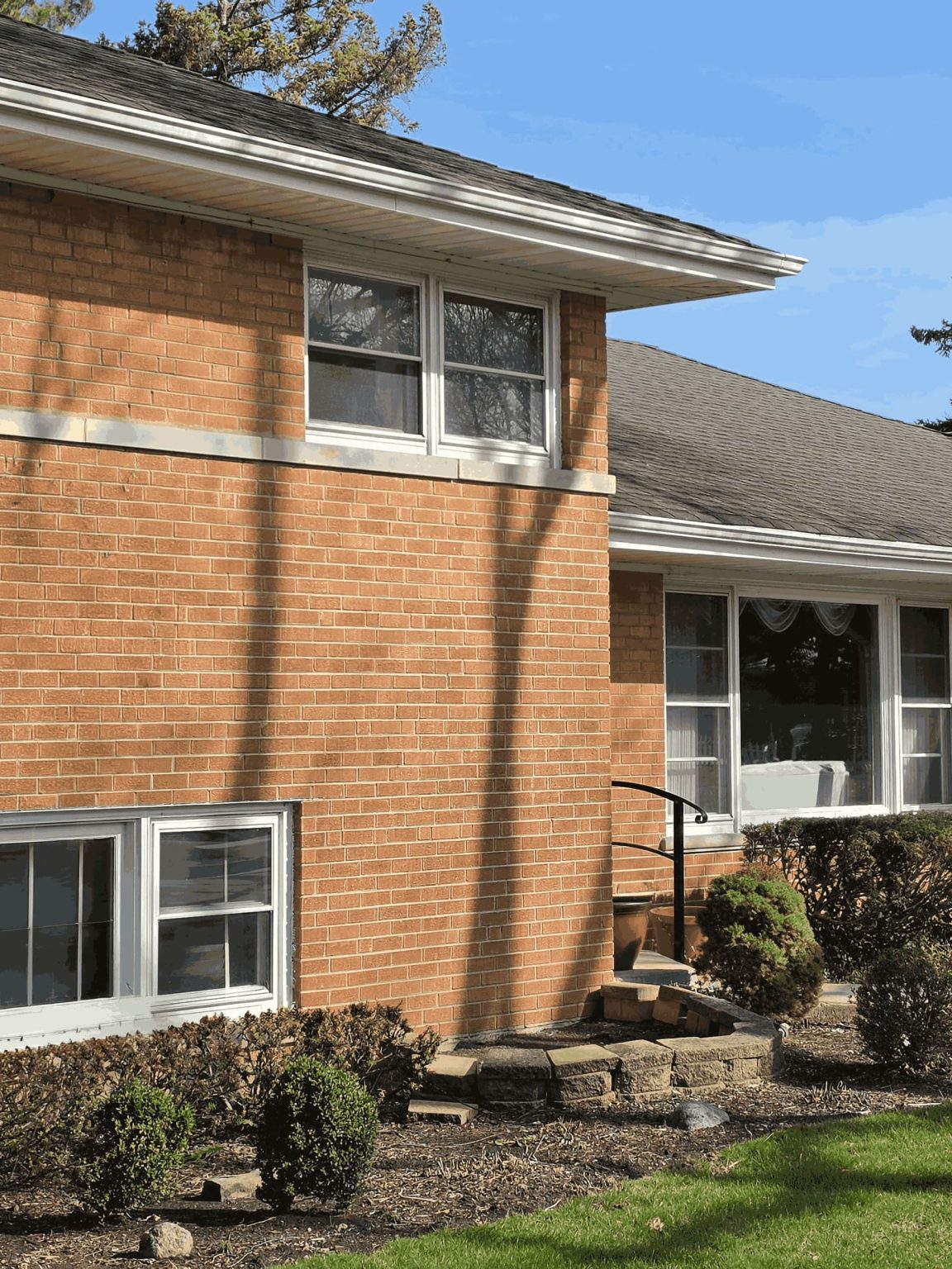 Brick split-level residence in Morton Grove, Illinois, with lower-level windows, mature landscaping, lawn, and an attached garage.