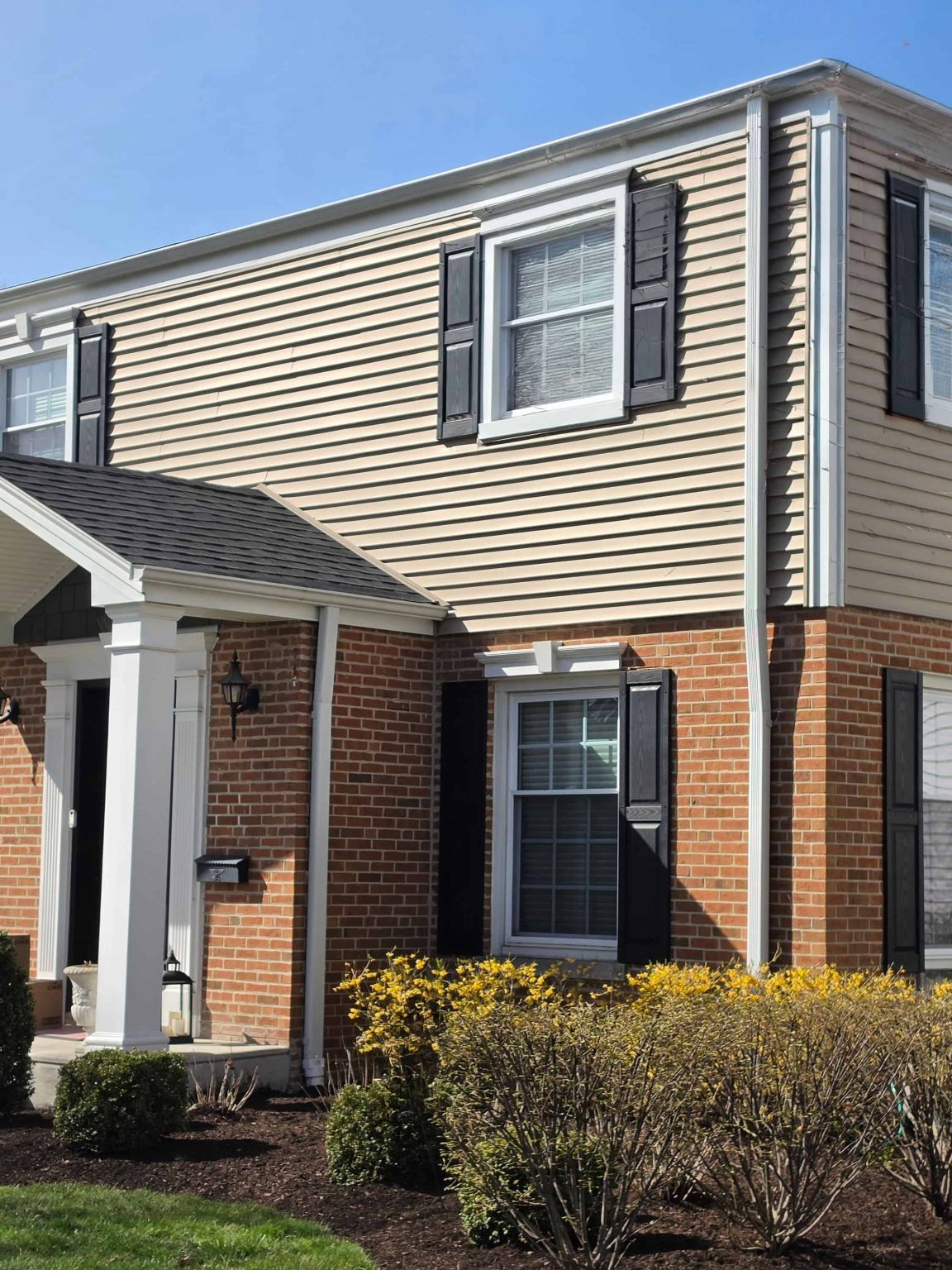 Brick and siding residence in Niles, Illinois, with a covered front entry, shutters, landscaped beds, and front lawn.