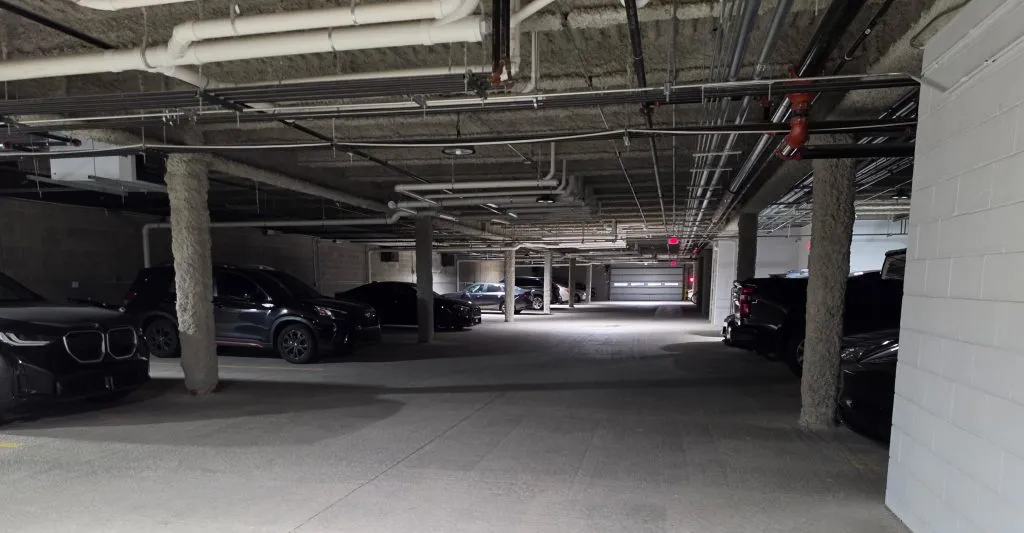 Parking-garage aisle with vehicles and a block wall.