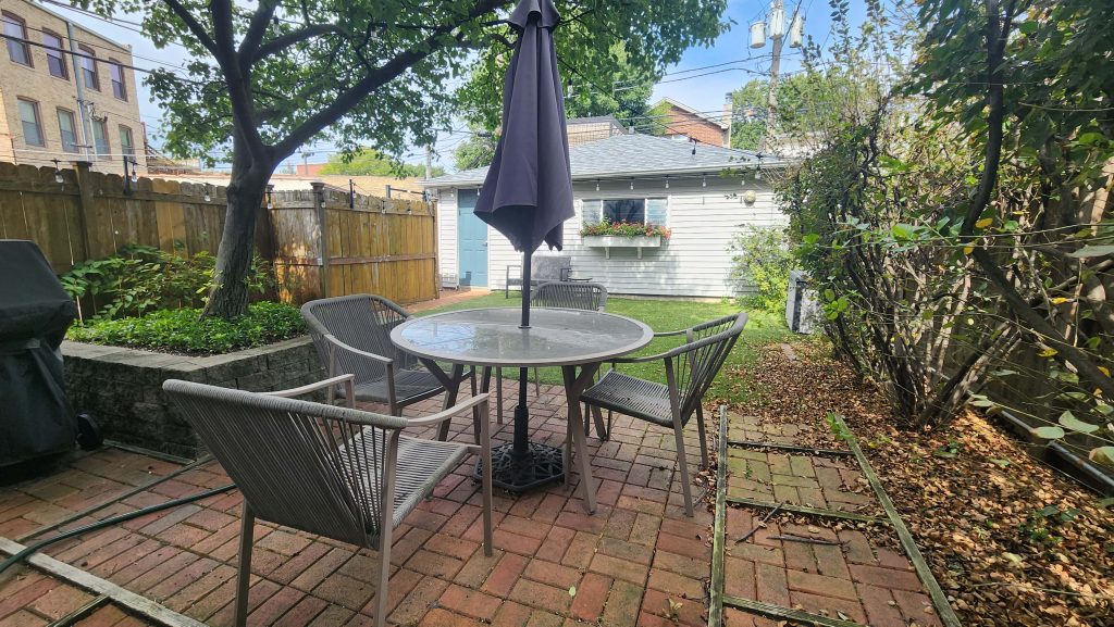 Patio seating beneath an umbrella beside garden planting.
