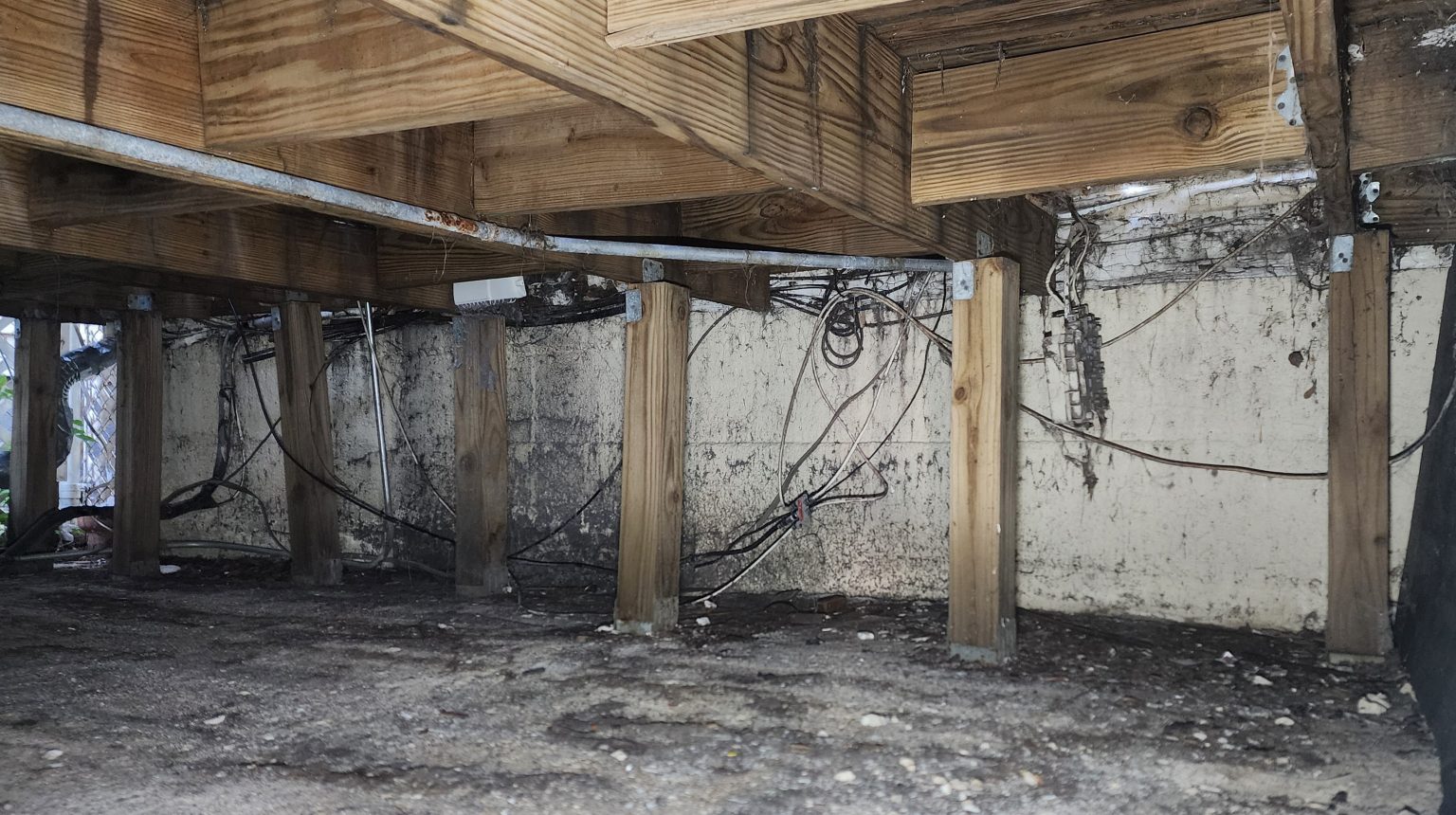 Foundation wall and ground beneath a wooden porch.