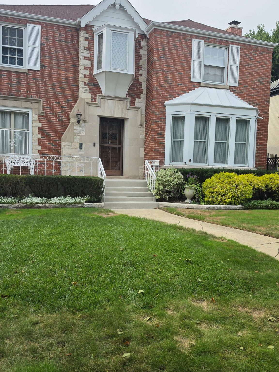 Brick residence in Sauganash, Chicago, with stone detailing, a landscaped front lawn, and neighboring residential homes.