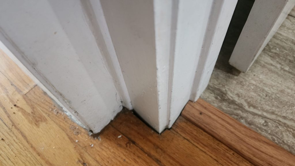 Painted door trim beside a wooden floor.