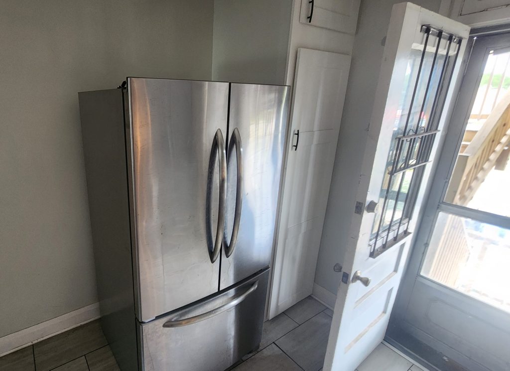 Refrigerator beside an open kitchen door.