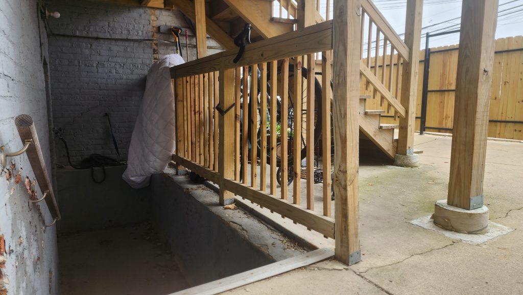 Wooden stairs beside a shaded basement stairwell.