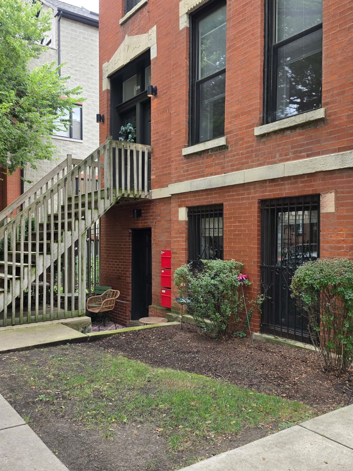 Brick residential buildings along a tree-lined sidewalk in Wicker Park, with raised entrances and small front gardens.